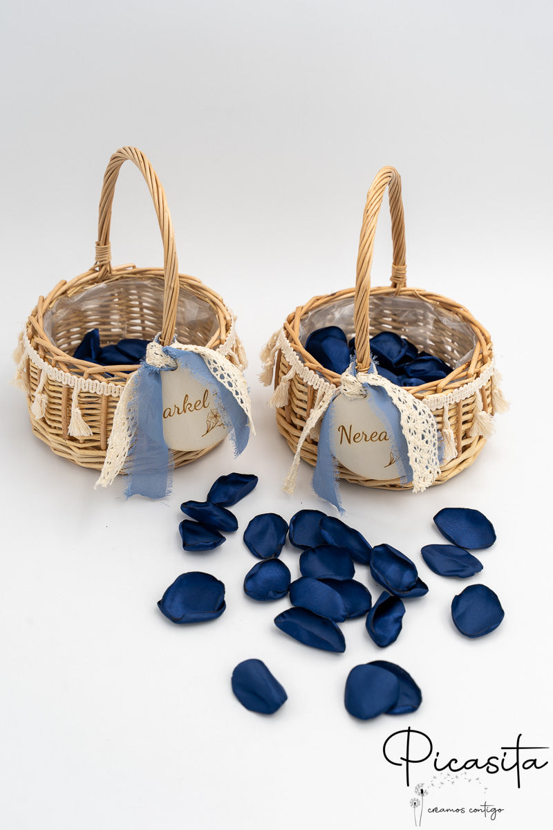 Dos cestas de ratán con pétalos azules, lazos celestes y etiquetas redondas de madera.