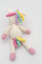 Vista completa trasera de un unicornio de crochet mostrando la cola y melena multicolor.