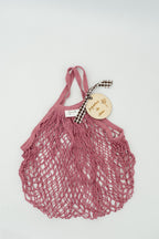 Bolsa de malla rosa oscuro con placa de madera grabada con el texto juguetes de olivia.