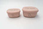 Dos tuppers rosa personalizados con el nombre Teresa y dibujos de dinosaurio