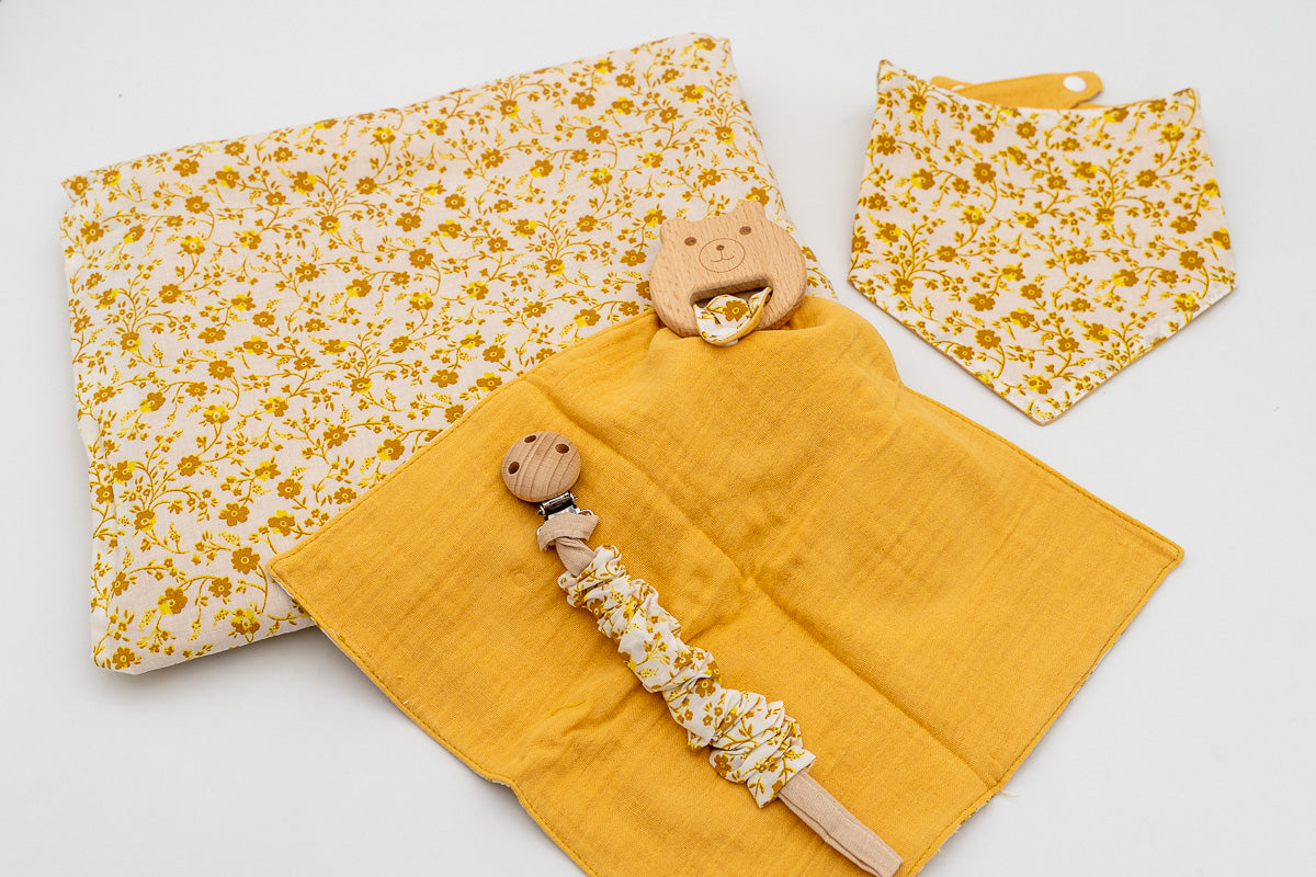 Set senape con copertina a fiori, bavaglino a bandana, mussola senape con massaggiagengive a orsetto in legno e catenella portaciuccio con clip in legno.