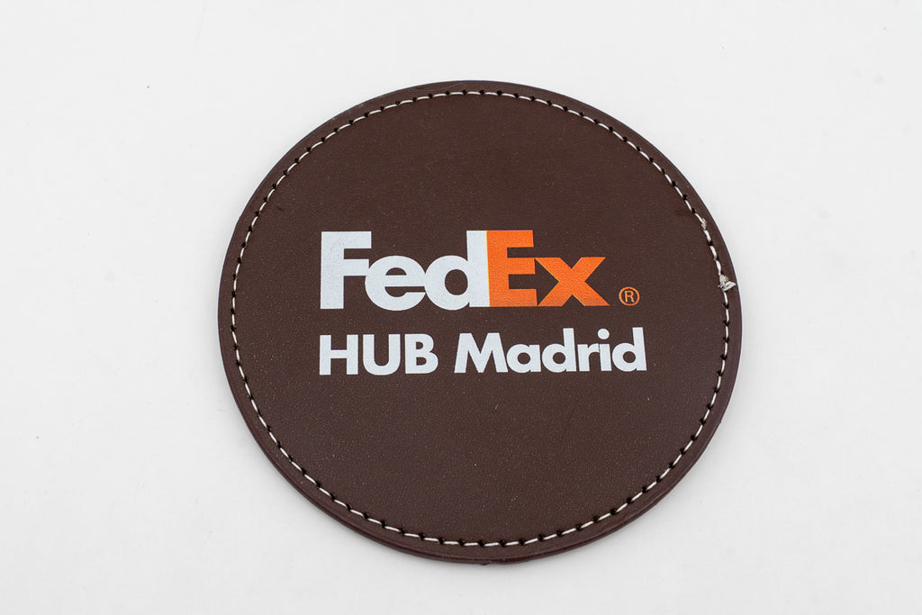 Sottobicchiere rotondo marrone con logo FedEx a colori.