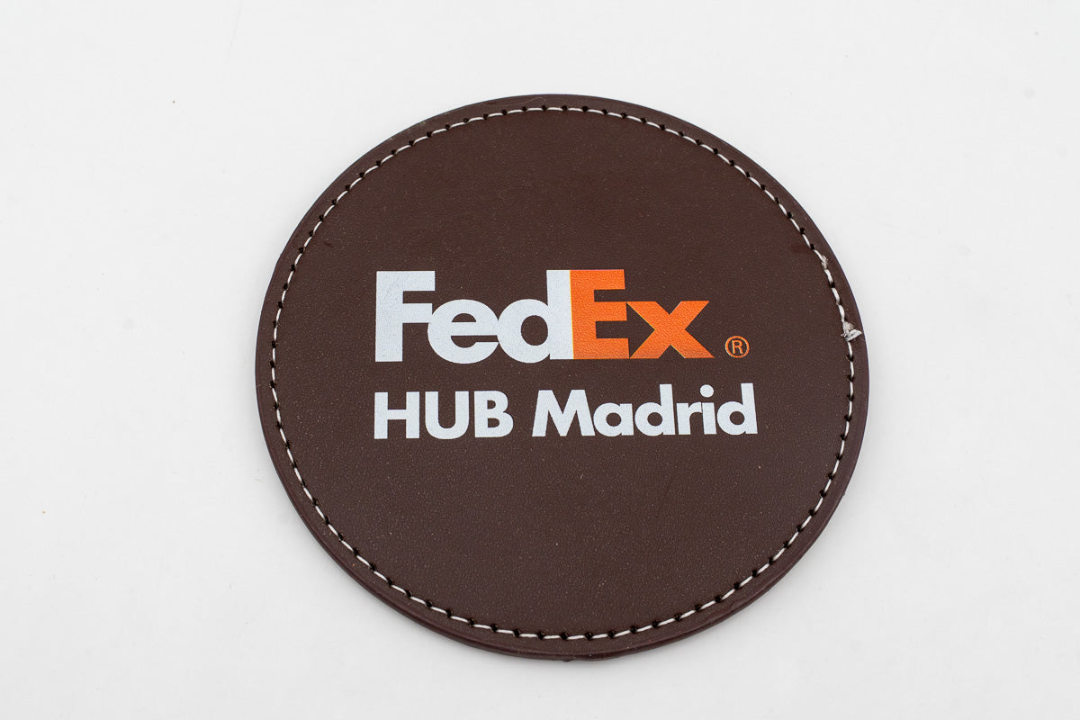 Sottobicchiere rotondo marrone con logo FedEx a colori.