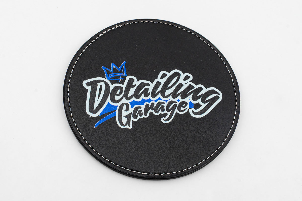 Sottobicchiere rotondo nero con logo Detailing Garage blu e giallo.