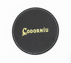 Sottobicchiere rotondo nero con logo Codorníu di tonalità dorata.