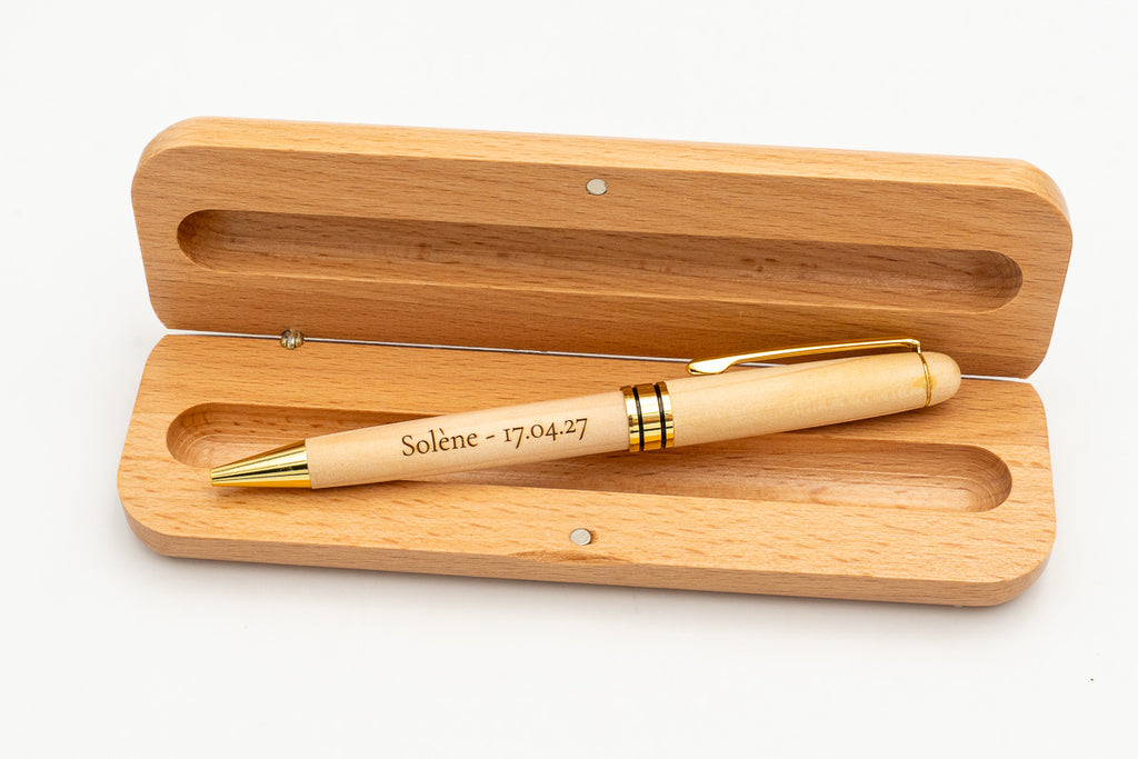 Astuccio aperto con penna in legno chiaro con cappuccio e dettagli dorati.