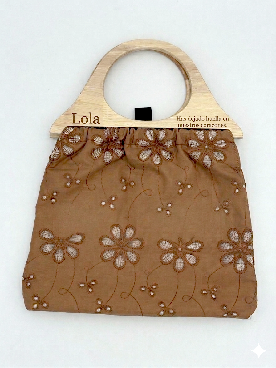Bolso de tela marrón con asa de madera grabada Lola y patrón calado de flores.