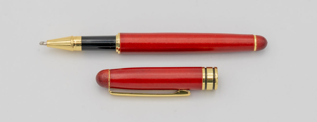 Penna in legno con finitura rossastra, cappuccio rimosso e dettagli dorati.