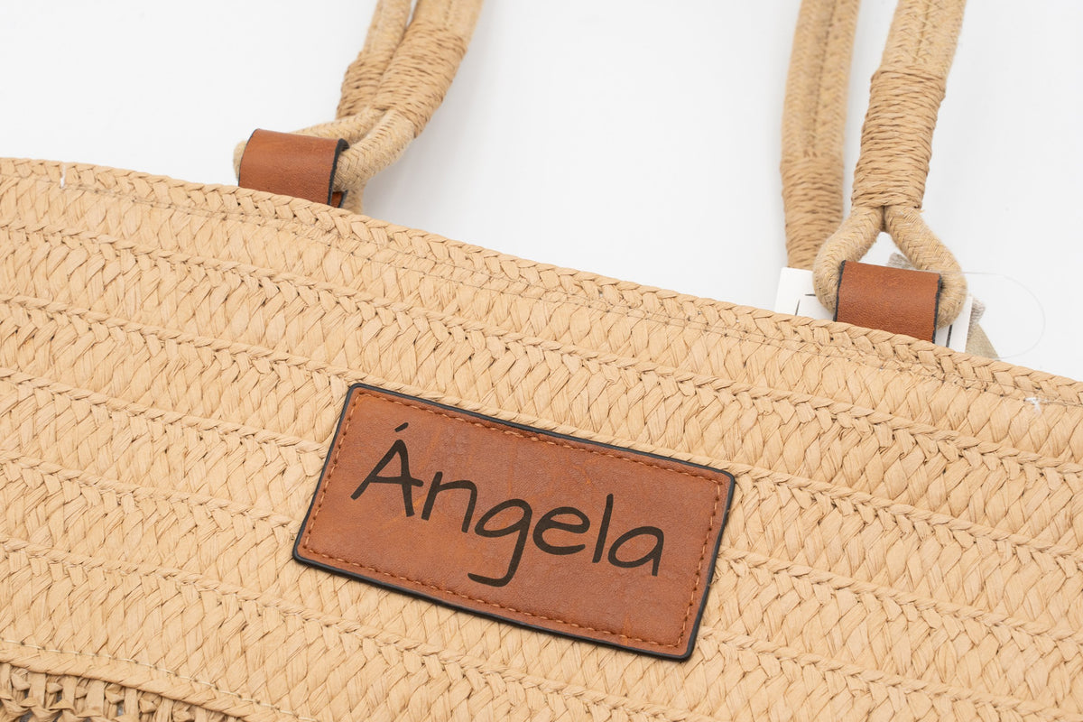 Patch in similpelle di una borsa di rafia inciso con il nome Ángela