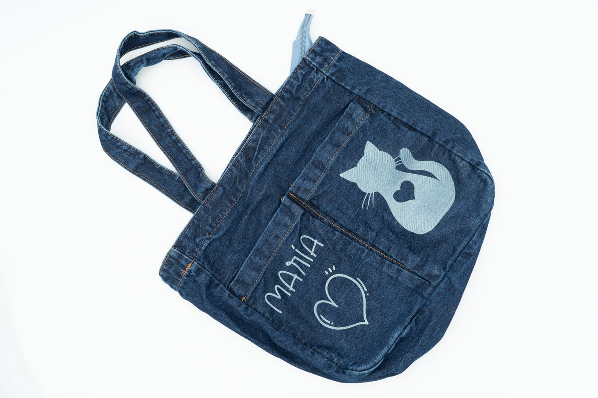 Bolso tote de tela vaquera azul oscuro con nombre María y dibujo de gato grabados a láser.