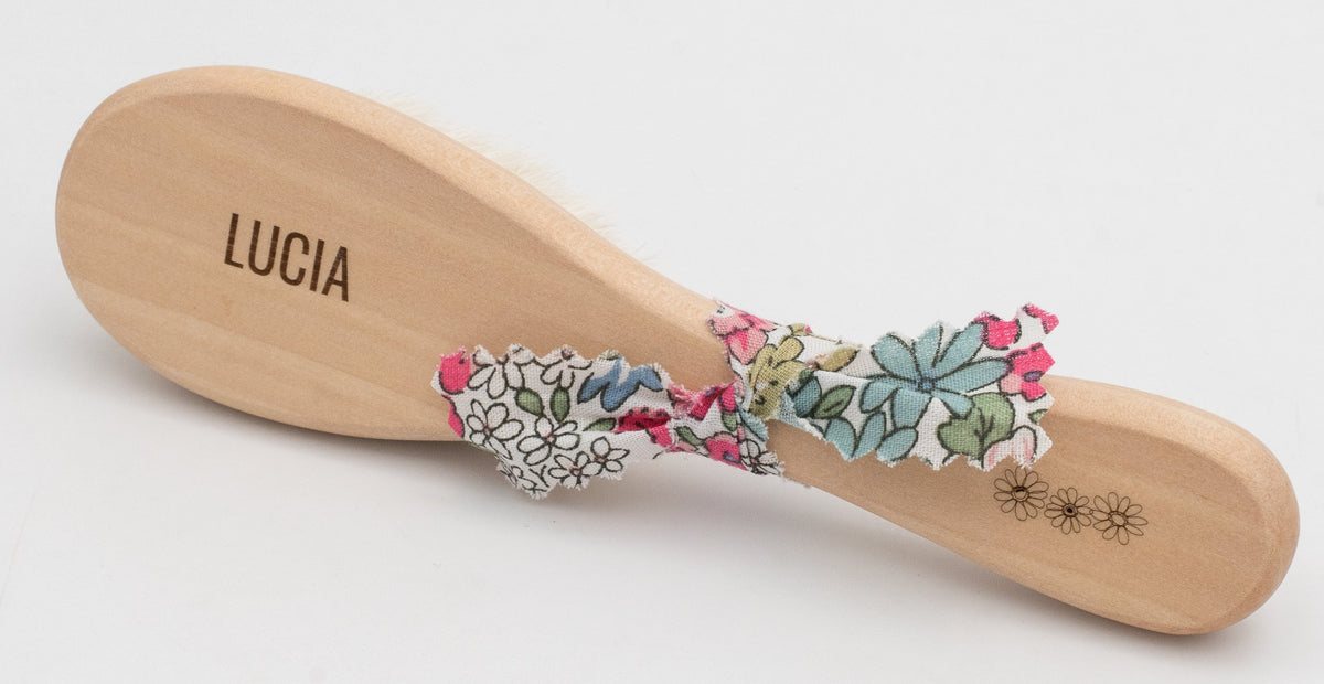 Spazzola in legno con il nome Lucía e fiori a colori.