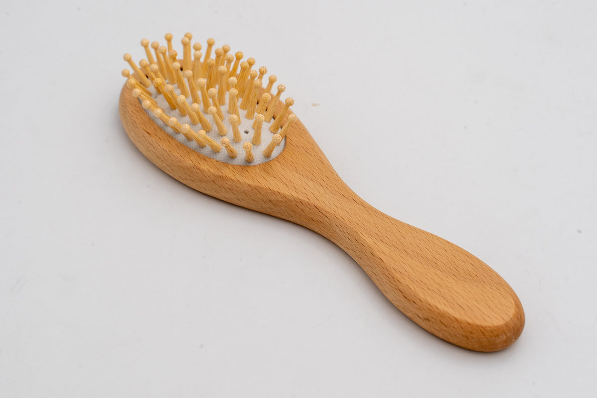 Spazzola con dentini in legno vista frontalmente su fondo bianco.