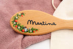 Dettaglio di una spazzola con il nome Martina e fiori a colori.