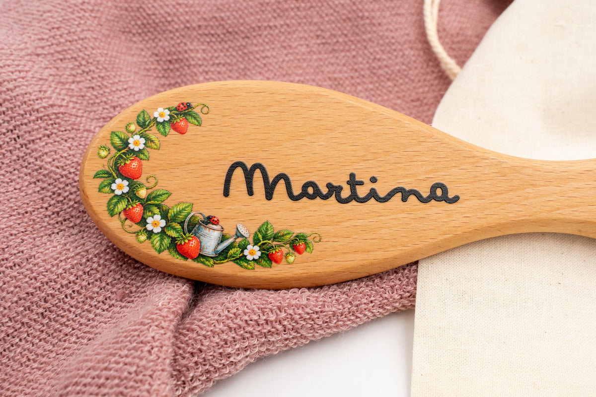 Dettaglio di una spazzola con il nome Martina e fiori a colori.