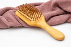 Spazzola rettangolare con dentini in legno vista frontalmente.