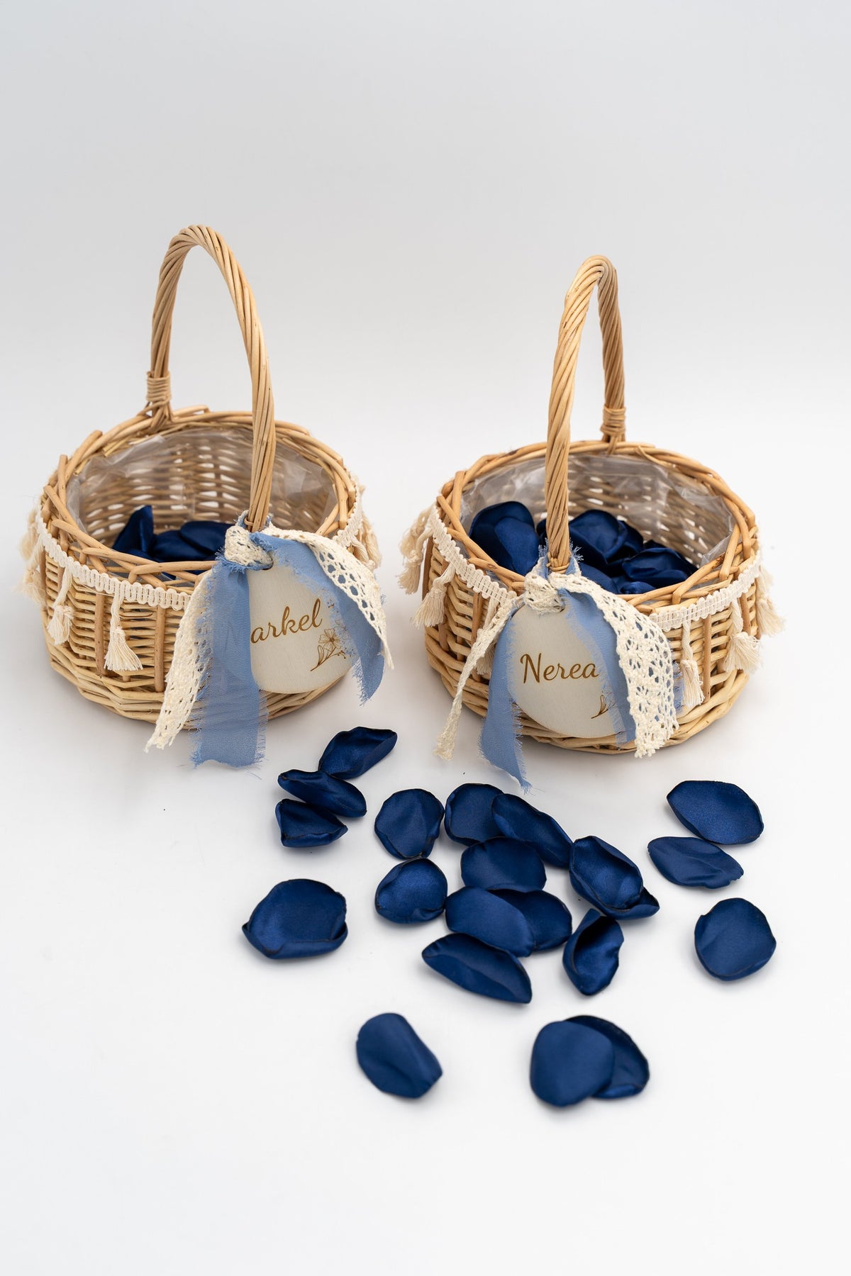 Due cesti in rattan con petali blu, fiocchi celesti ed etichette rotonde in legno