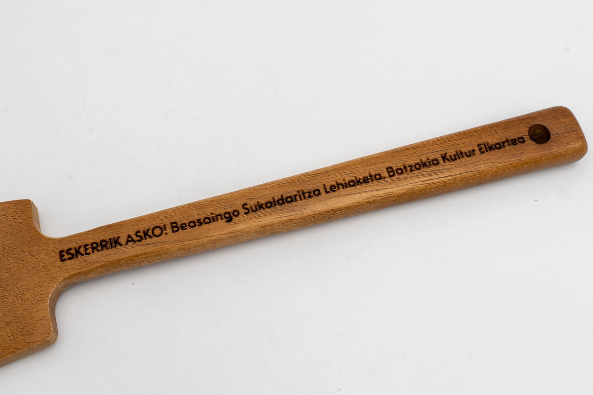 Mango de madera oscura con frase grabada en euskera sobre fondo neutro.