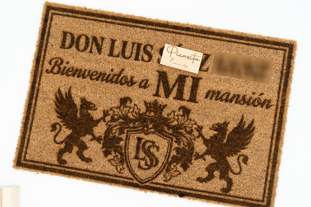 Felpudo con escudo heráldico y figuras de grifos grabado para entrada de mansión.