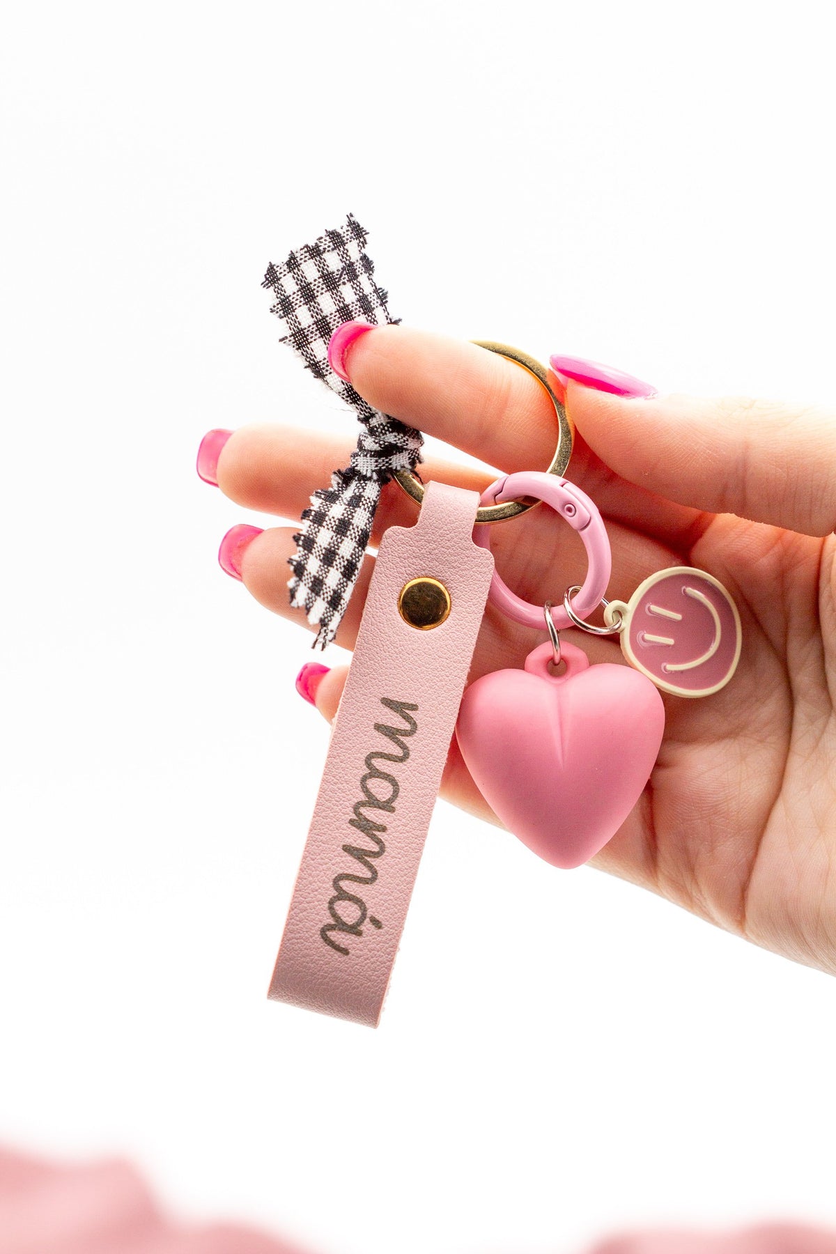Primer plano de llavero rosa para mamá con detalles dorados y charms decorativos sobre fondo blanco.