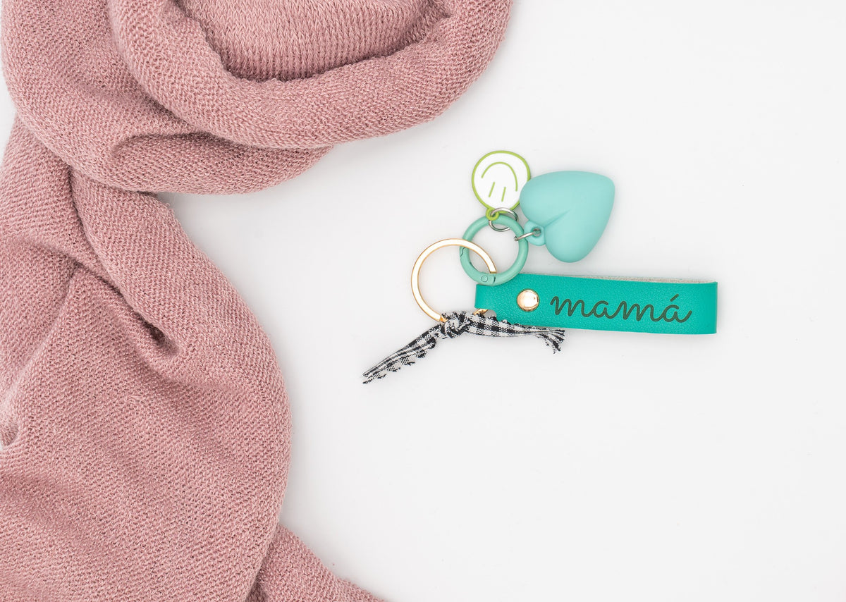 Llavero personalizado color aguamarina con grabado láser, corazón de silicona y carita sonriente metálica.