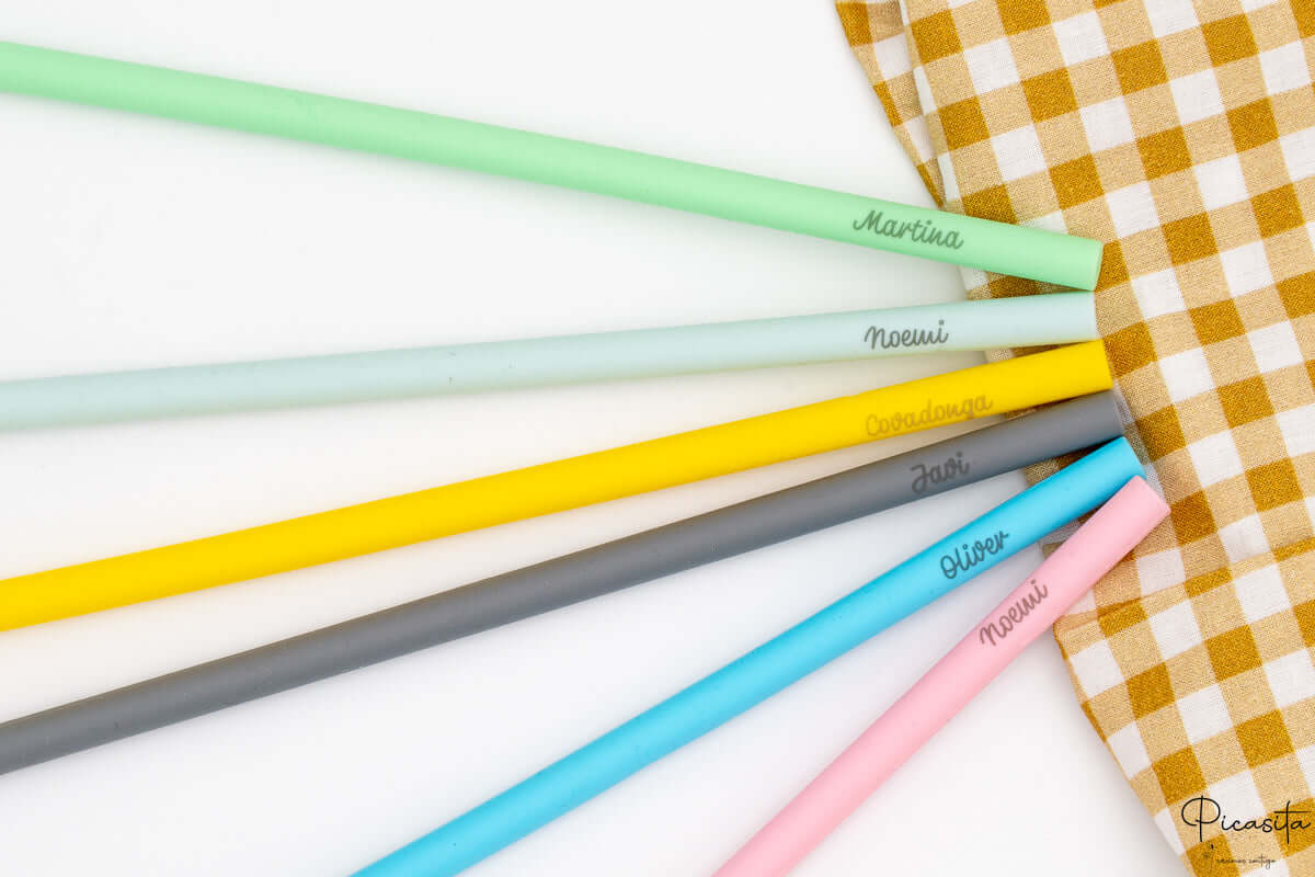 Detalle de nombres grabados a láser sobre pajitas de silicona de varios colores.