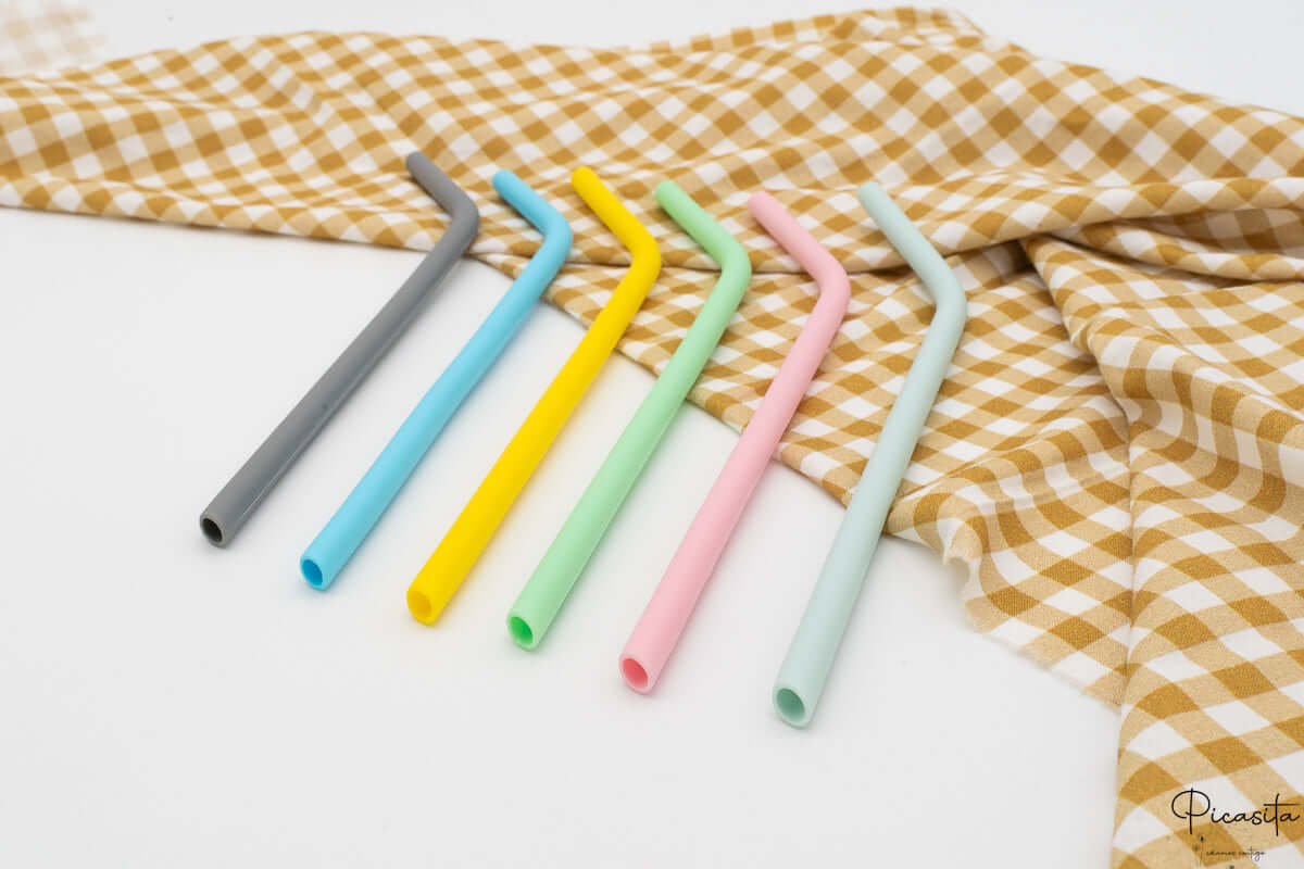 Pajitas de silicona flexibles con forma curva junto a un paño de cuadros.