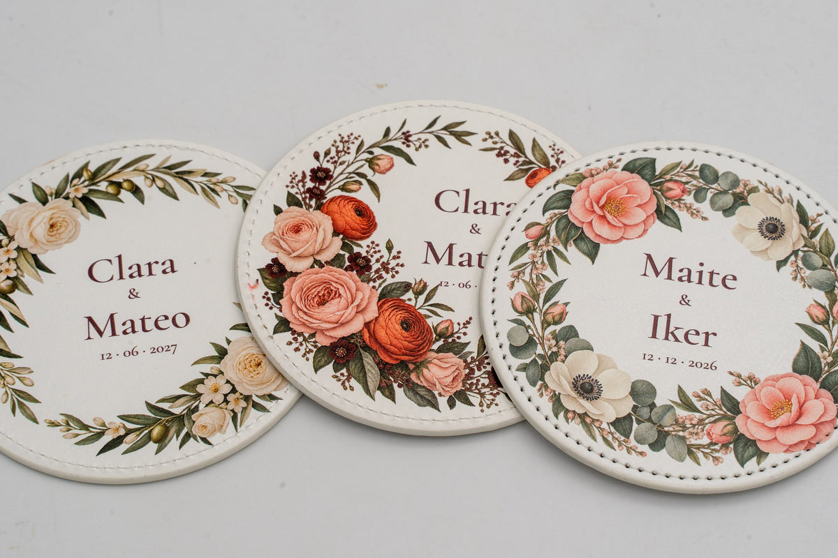 Tre sottobicchieri rotondi bianchi con fiori a colori e nomi degli sposi.
