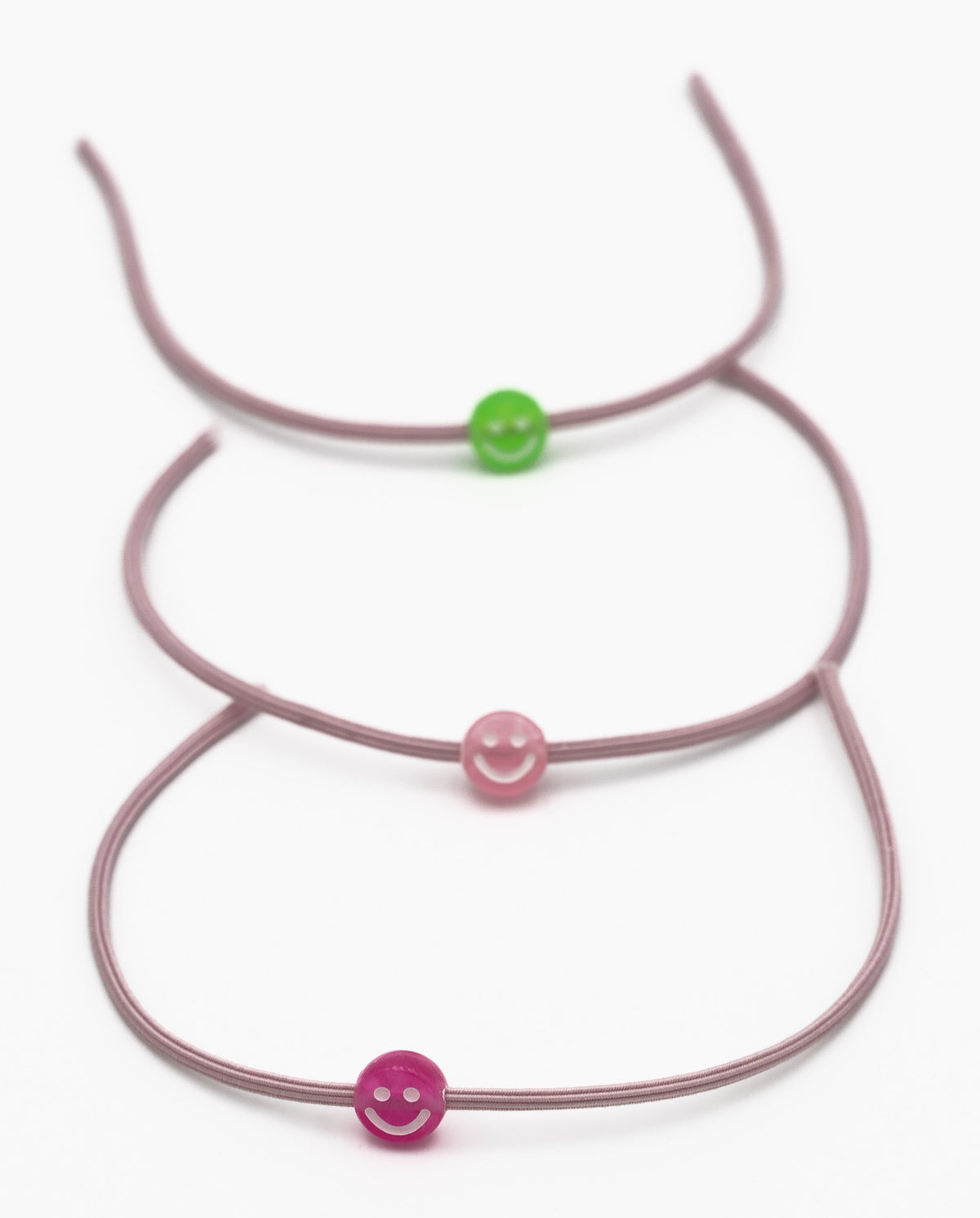 Tre braccialetti elastici malva con perline in silicone a forma di sorriso verdi e rosa