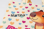 Detalle del nombre personalizado en vinilo negro sobre bolsa de algodón con ilustración de capibara.