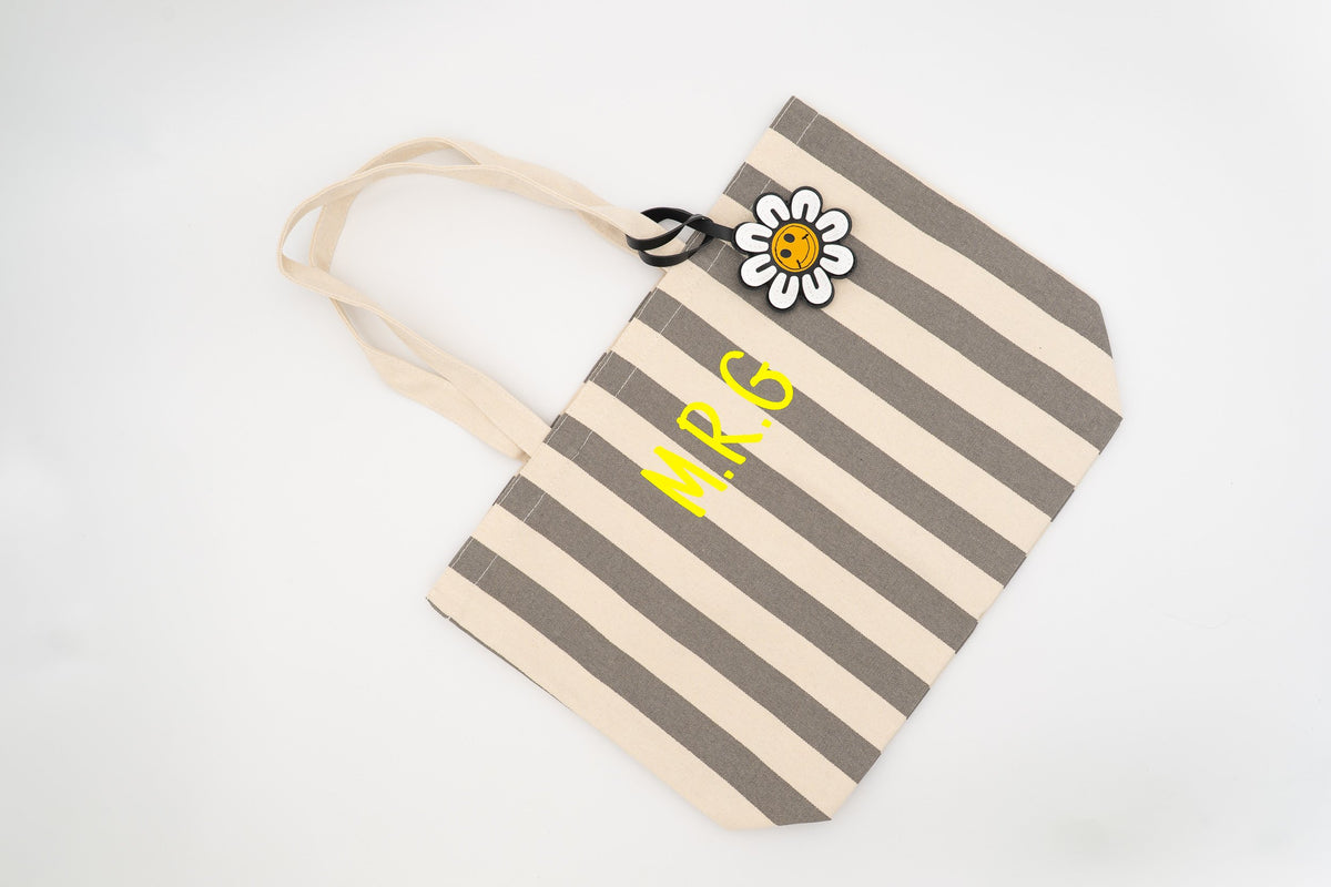 Borsa da piscina a righe grigie e bianche decorata con un ciondolo a margherita